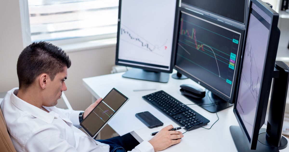 Trader frente a varias pantallas con gráficos